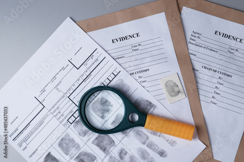 Fingerprint card, magnifying glass on background of evidence packaging