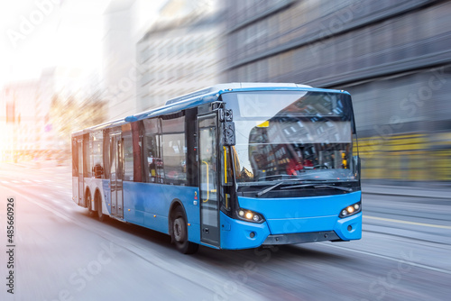 Blue bus moving on the road in city in early morning.