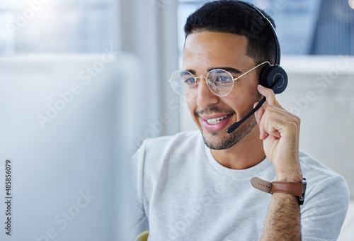 Hi there how may I be of service. Shot of a young businessman working at his desk in his office.