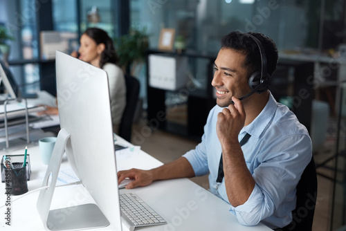 Understanding starts with listening. Shot of a young man using a headset and computer in a modern office.