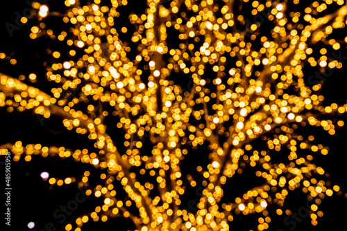 garland of yellow color close-up on a tree, the background is dark. Photo in the bokeh style.