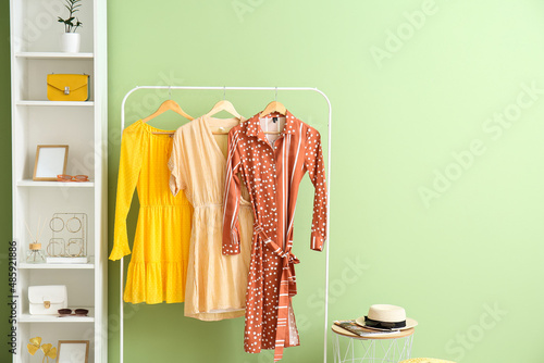 Hanger with dresses and shelf unit with accessories near color wall