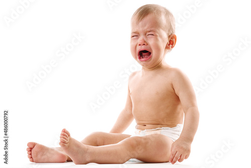 Upset little boy in diaper sitting and crying.