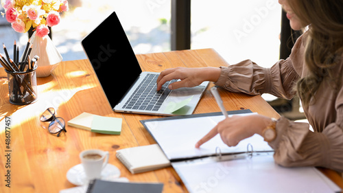 Employee checks and compares the details on a document between laptops.