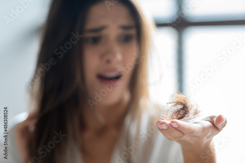 Closeup Of Stressed Young Woman Holding Bunch Of Fallen Hair In Hand