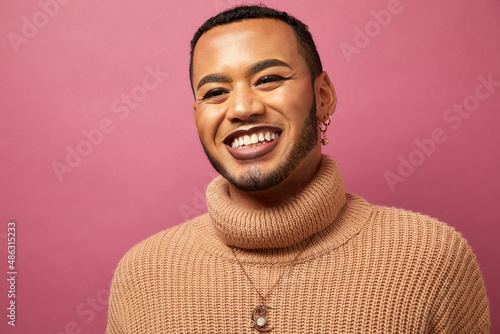 Studio portrait of smiling queer man against purple background