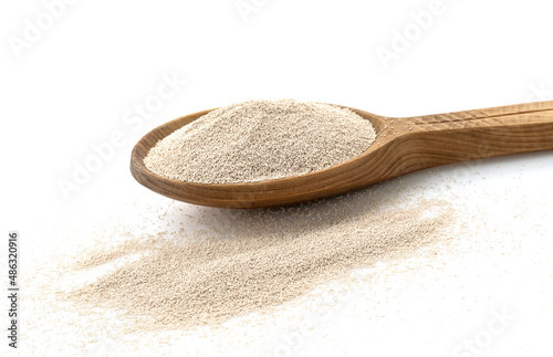 Dry yeast in wooden scoop isolated on white background