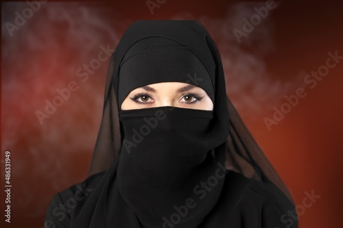 Portrait of young woman in black burqa with hidden face,