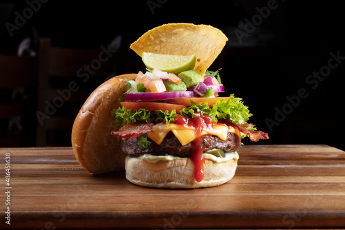 Hamburguesa con queso guacamole abierta, sobre una tabla de madera. Open burger with guacamole cheese, on a wooden board.