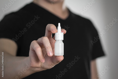 A man holds a spray for a runny nose. Close up