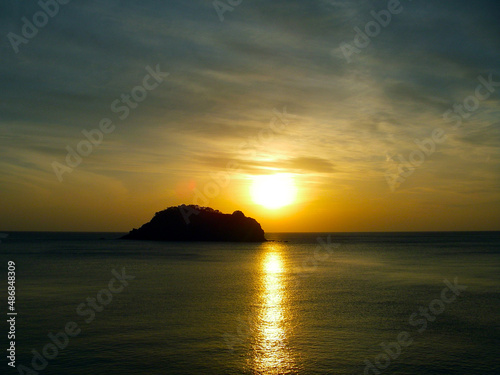 Gold shining sunset sea view with a island silhouette image photography. 西伊豆から観る海面を黄金色に照らす宇留井島に向かって落ちる夕陽。