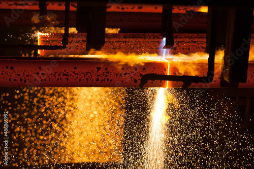 Manufacturing of mild steel square bar on continuous casting machine. Cutting bars by gas torch flame. Metal sparks.