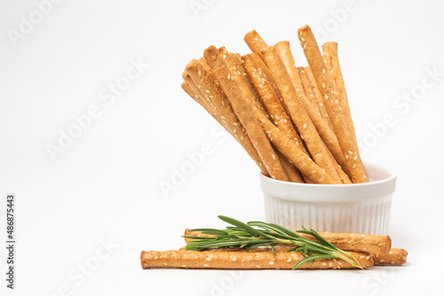 Classic crispy Italian bread sticks with rosemary and sesame seeds in white form. Traditional breadsticks grissini on white background with copy space