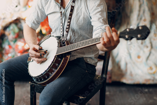 Male musician playing banjo sitting chair indoor