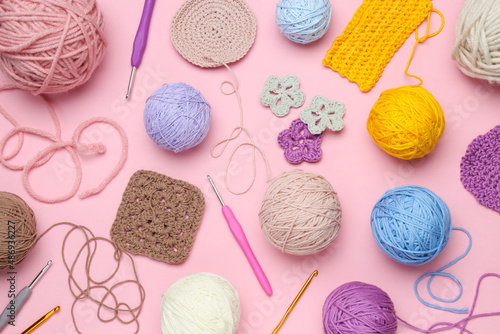 Flat lay composition with knitting threads and crochet hooks on pink background