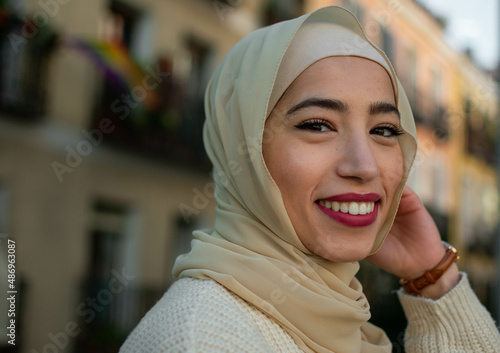 Pretty young muslim woman in hijab scrolling outdoors 