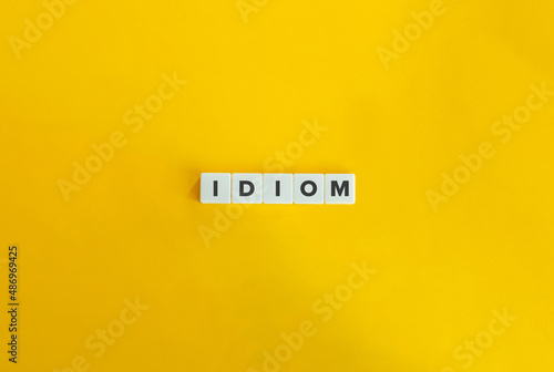 Idiom Word on Letter tiles on bright orange background. Minimal aesthetics.