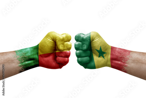 Two hands punch to each others on white background. Country flags painted fists, conflict crisis concept between benin and senegal