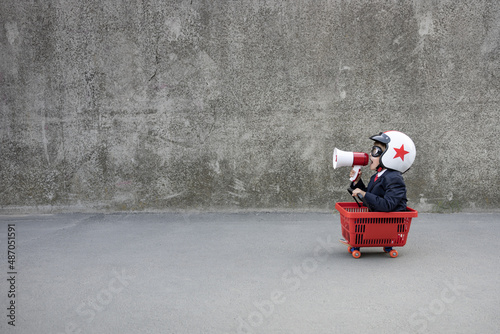 Funny businessman riding shopping cart outdoor