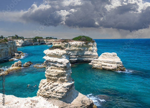 Melendugno,province of Lecce, Puglia, Italy. August 2021. The stacks of Sant'Andrea are a point of naturalistic attraction: the amazing landscape suggests a tropical destination. People taking a bath.