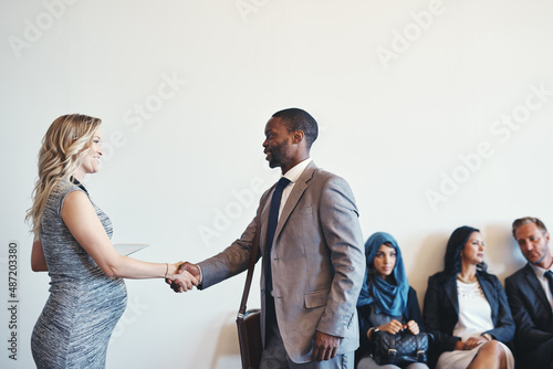Are you ready for the interview. Shot of a cheerful young business receiving a handshake from a businesswoman while waiting for a interview inside of a office during the day.