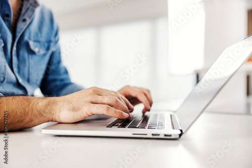 Side view of male hands typing on the laptop.