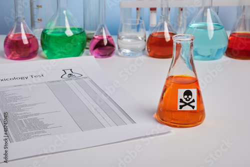 Toxic report for orange juice and colored chemical flasks. Toxicology analysis for food safety of orange drink. Food control of colored fluids. Paper report page of poison component analysis.