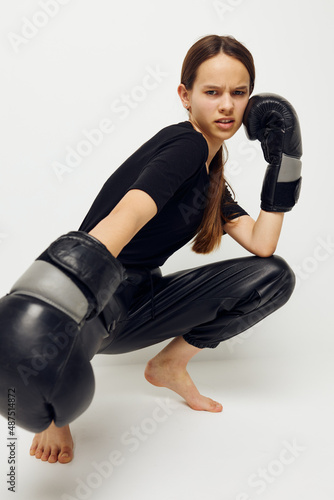 beautiful girl in boxing gloves on the floor in black t-shirt light background