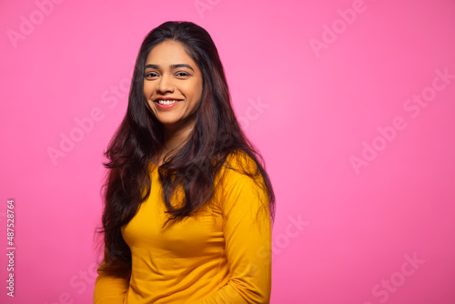 Young woman in yellow dress posing in front of camera with smile
