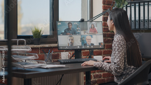 Employee talking to workmates on online video call, meeting to discuss business project. Woman using remote teleconference on computer with colleagues. Video conference on webcam