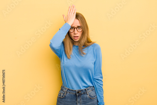 pretty caucasian woman raising palm to forehead thinking oops, after making a stupid mistake or remembering, feeling dumb