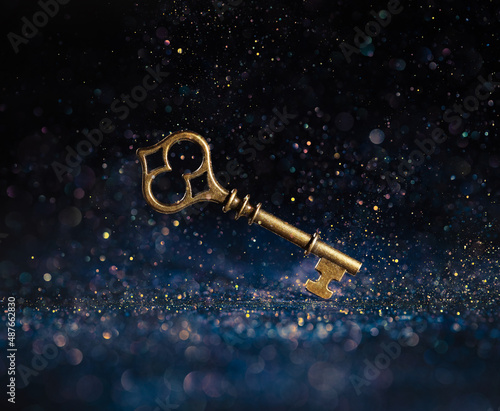 Single golden skeleton key surrounded by sparkling lights. Business concepts of unlocking potential, key to success, or financial opportunity.