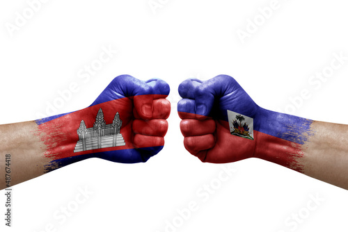 Two hands punch to each others on white background. Country flags painted fists, conflict crisis concept between cambodia and haiti