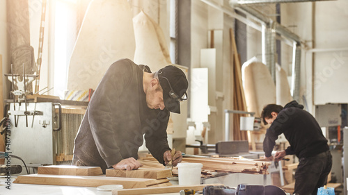 Custom projects with artistic, design oriented value. Portrait of caucasian worker holding a brush, applying varnish paint on a wooden furniture