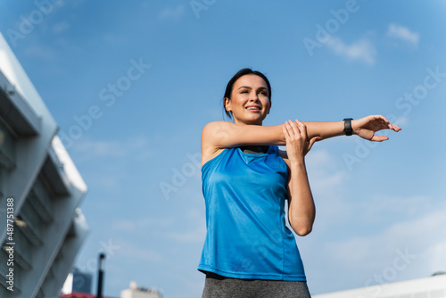 Pleased fit woman performing upper limb stretching exercise