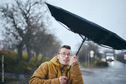 Man holding broken umbrella in strong wind during gloomy rainy day. Themes weather, meteorogy and climate changes..