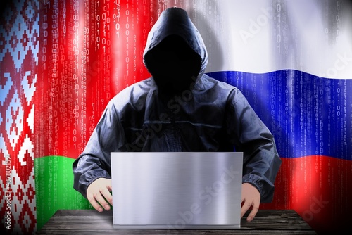 Anonymous hacker working on a laptop, flags of Belarus and Russia