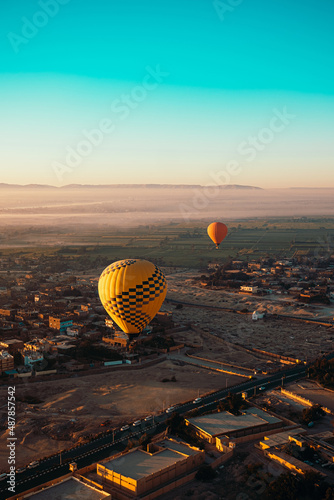 Wonderful vertical shot of two balloons flying on low altitude above the houses in luxor egypt. Landscapes of egypt in the distance, early morning