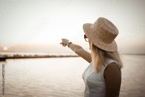 Young woman in shyalpa shows her finger to the sky at sunrise on the beach