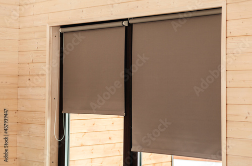 Roller Blinds on Window on Wooden Wall. Modern sunproof blinds grey pastel color 