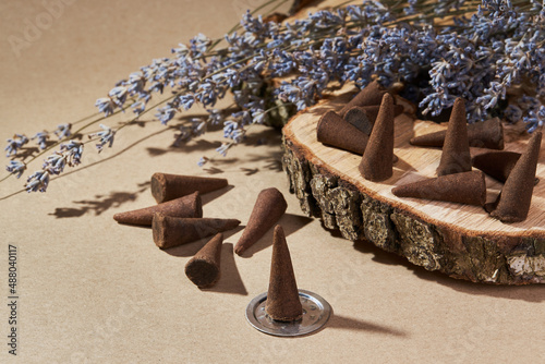 Incense cones for aromatherapy with lavender flowers on a brown background. Burning incense cone 