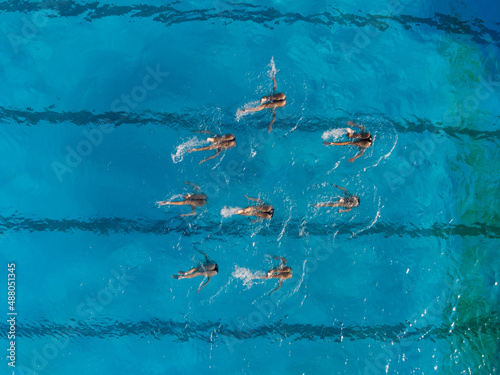 Aerial view of group synchronized swimmers performance with legs