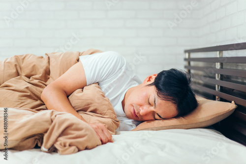 ベッドで寝る男性 