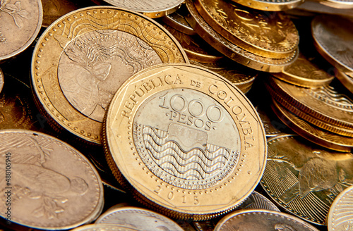 monedas de mil pesos colombianos sobre un montón de otras monedas de mas bajo valor comercial 