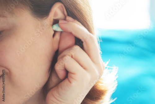 noise insert,woman puts a plug in her ear before going to bed so that the noise does not interfere with sleep