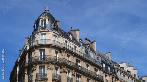 Immobilier ancien à Paris, architecture de la façade d'un immeuble d’angle haussmannien avec balcon (France)