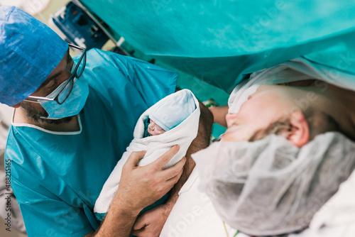 Male doctor showing newborn baby to mother