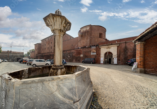 Saluzzo, Cuneo, Italy - October 19, 2021: Piazza Castello with the Drancia fountain and Castile fortress (13th century) was a prison now the Museum of Knightly Civilization and of Prison Memory