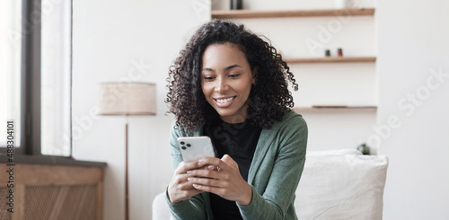 Young woman using smartphone at home. Mixed race girl looking at mobile phone. Communication, social distancing, connection, mobile apps, technology, lifestyle concept