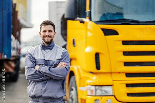 An import and export firm driver posing with trucks and smiling at the camera.